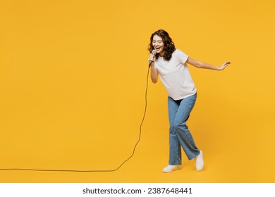 Full body singer happy fun young woman she wear white blank t-shirt casual clothes sing song in microphone at karaoke club isolated on plain yellow orange background studio portrait. Lifestyle concept - Powered by Shutterstock