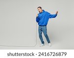 Full body singer young middle eastern man wear blue hoody casual clothes sing song in microphone at karaoke club spread hand isolated on plain solid white background studio portrait. Lifestyle concept