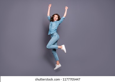 Full body size length of nice crazy cheerful attractive brunette girl with wavy hair in casual denim shirt and jeans, jumping in air, dancing, celebrating, isolated over grey background