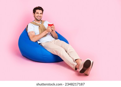 Full body size photo of relaxed young man lying bean bag drink sweet cacao coffee break work time isolated on pink color background - Powered by Shutterstock