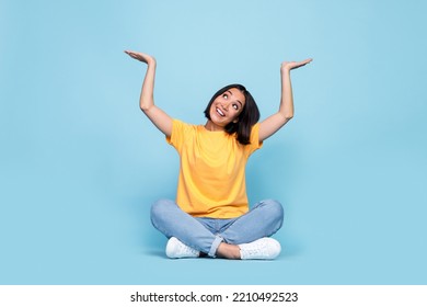Full body size photo of young japanese pretty girl bob brunette hair interested look up hold palms object advert empty space isolated on blue color background - Shutterstock ID 2210492523