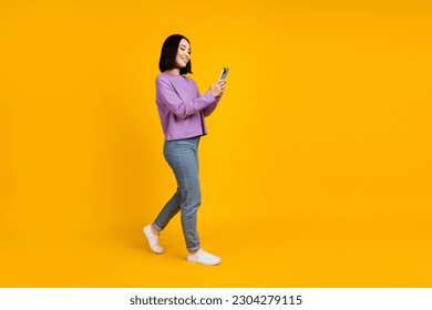 Full body size photo of young chinese blogger girl hold phone walking recording video online popularity isolated on yellow color background - Powered by Shutterstock