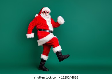 Full body size profile photo of retired grandpa funny walk together elves deer buy present gift kids wear red santa costume coat gloves sunglass cap isolated green color background - Powered by Shutterstock