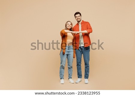 Full body smiling cheerful fun young couple two friends family man woman wear casual clothes together giving fist bump look camera isolated on pastel plain light beige color background studio portrait