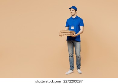 Full body smiling fun delivery guy employee man wear blue cap t-shirt uniform workwear work as dealer courier hold pizza in cardboard flatbox isolated on plain light beige background. Service concept - Powered by Shutterstock