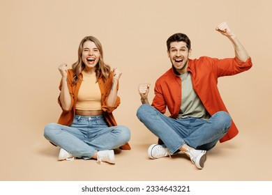 Full body smiling fun young couple two friends family man woman wear casual clothes together sitting do winner gesture clench fist isolated on pastel plain light beige color background studio portrait - Powered by Shutterstock