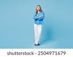 Full body smiling happy cheerful young woman she wear shirt casual clothes hold hands crossed folded look camera isolated on plain pastel light blue cyan background studio portrait. Lifestyle concept