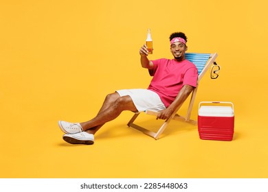 Full body smiling happy cheerful fun young man 20s he wear pink t-shirt bandana near hotel pool raise toast drink beer look camera isolated on plain yellow background. Summer vacation sea rest concept - Powered by Shutterstock