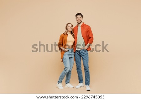 Full body smiling happy cheerful fun cool young couple two friends family man woman wear casual clothes together looking camera hugging isolated on pastel plain beige color background studio portrait