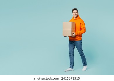 Full body smiling happy fun young man he wears orange hoody casual clothes hold stack cardboard blank boxes isolated on plain pastel light blue cyan color background studio portrait. Lifestyle concept - Powered by Shutterstock