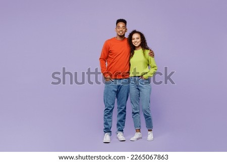 Full body smiling happy fun cheerful young couple two friends family man woman of African American ethnicity wear casual clothes together hugging look camera isolated on plain light purple background