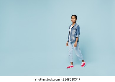 Full body smiling happy little kid teen girl of African American ethnicity 12-13 years old in denim jacket walking going look camera isolated on pastel plain light blue background. Childhood concept - Shutterstock ID 2149310349