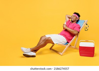 Full Body Smiling Happy Minded Fun Young Man 20s He Wearing Pink T-shirt Bandana Near Hotel Pool Drink Beer Hold Hand Behind Neck Isolated On Plain Yellow Background. Summer Vacation Sea Rest Concept