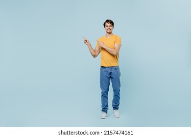 Full Body Smiling Happy Young Man 20s Wear Yellow T-shirt Point Index Finger Aside On Workspace Area Mock Up Isolated On Plain Pastel Light Blue Background Studio Portrait. People Lifestyle Concept