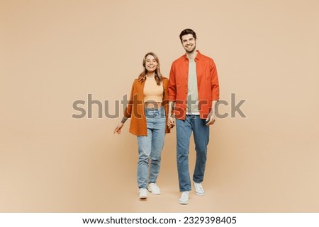 Full body smiling hapy young couple two friends family man woman wear casual clothes walking strolling going hold hands together isolated on pastel plain light beige color background studio portrait