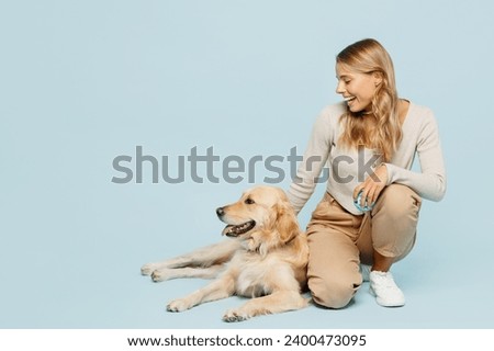 Full body smiling satisfied young owner woman wear casual clothes kneeling hug cuddle embrace her best friend retriever dog isolated on plain light blue background studio. Take care about pet concept
