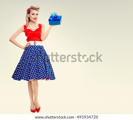 Full body of smiling woman dressed in pin-up style dress with polka dot. Caucasian blond model posing in retro fashion and vintage concept shoot. Copyspace area for advertising slogan or text message.