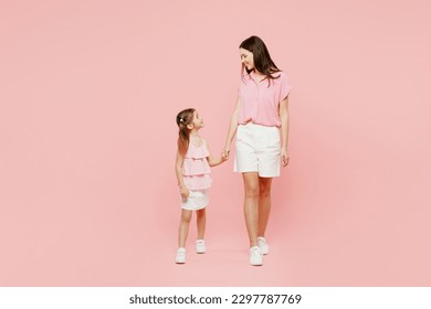 Full body smiling woman wear casual clothes with child kid girl 6-7 years old. Mother daughter look to each other hold hands walk isolated on plain pastel pink background. Family parent day concept - Powered by Shutterstock