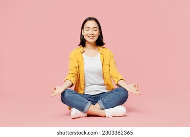 Full body spiritual young woman of Asian ethnicity wear yellow shirt white t-shirt hold spread hands in yoga om aum gesture relax meditate try calm down isolated on plain pastel light pink background - Shutterstock ID 2303382365
