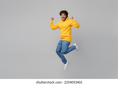 Full body successful lucky fun young Indian man 20s he wearing casual yellow hoody jump high do winner gesture clench fist isolated on plain grey background studio portrait. People lifestyle portrait - Shutterstock ID 2254053401