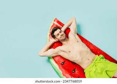 Full body top view from above young man wear green shorts swimsuit relax near hotel pool lying on red mattress close eyes isolated on plain blue background. Summer vacation sea rest sun tan concept - Powered by Shutterstock