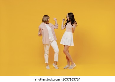 Full Body Two Young Smiling Happy Daughter Mother Together Couple Women Wear Casual Beige Clothes Do Winner Gesture Clench Fist Isolated On Plain Yellow Background Studio. Family Lifestyle Concept.