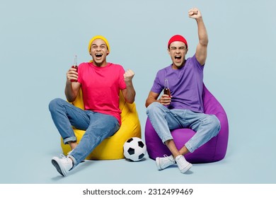 Full body winner fans couple two friends men wear casual clothes together sit in bag chair support football sport team hold beer soccer ball cup watch tv live stream isolated on plain blue background - Powered by Shutterstock