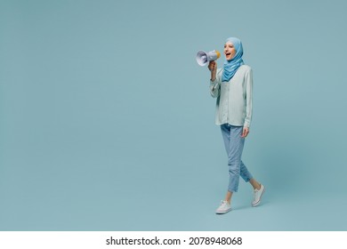 Full body young arabian asian muslim woman in abaya hijab hold scream in megaphone announces discounts sale Hurry up isolated on plain blue background People uae middle eastern islam religious concept