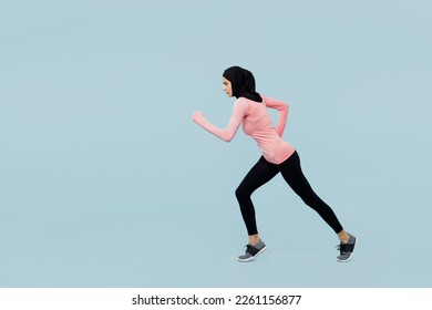 Full body young asian muslim fitness trainer sporty woman wear pink abaya hijab spend time in gym stand at start going to run isolated on plain blue background studio. Workout sport fit abs concept - Powered by Shutterstock