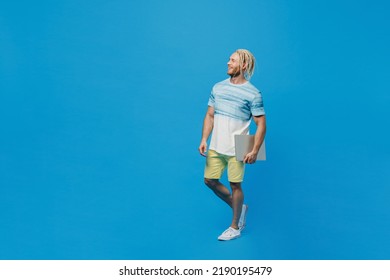 Full Body Young Blond Man With Dreadlocks 20s He Wear White T-shirt Hold In Hand Closed Laptop Pc Computer Look Aside On Workspace Area Isolated On Plain Pastel Light Blue Background Studio Portrait.