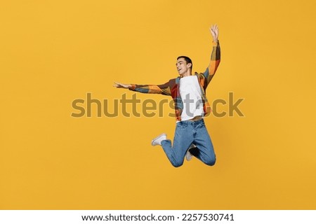 Full body young carefree middle eastern man wear casual shirt white t-shirt jump high with outstretched hands like flying isolated on plain yellow background studio portrait People lifestyle concept