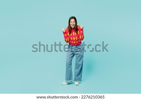 Full body young caucasian woman wear bright casual clothes doing winner gesture celebrate clenching fists say yes isolated on plain pastel light blue cyan background studio portrait. Lifestyle concept