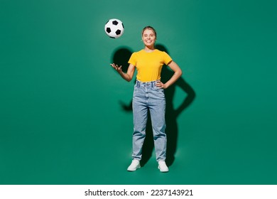 Full body young cool happy woman fan wear yellow t-shirt cheer up support football sport team hold in hand toss up soccer ball look camera watch tv live stream isolated on dark green background studio - Powered by Shutterstock