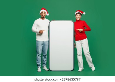 Full body young couple man woman wearing red casual clothes Santa hat posing point on big huge blank screen mobile cell phone isolated on plain green background. Happy New Year 2024 Christmas concept - Powered by Shutterstock