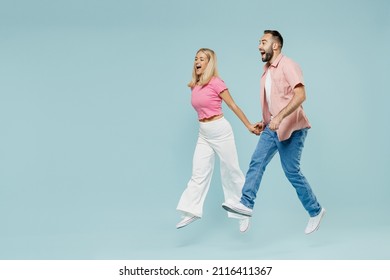 Full body young couple two friends family man woman in casual clothes jump high hurrying up go walk together isolated on pastel plain light blue background studio portrait People lifestyle concept.