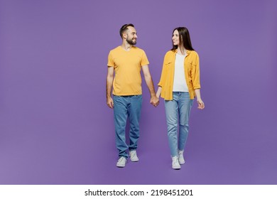 Full body young couple two friends family man woman together wearing yellow casual clothes looking to each other hold hands walking going strolling isolated on plain violet background studio portrait - Shutterstock ID 2198451201