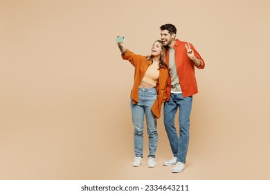 Full body young couple two friends family man woman wear casual clothes together do selfie shot on mobile cell phone post photo on social network isolated on pastel plain light beige color background