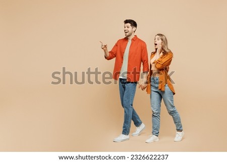 Full body young couple two friends family man woman wear casual clothes together point index finger aside indicate on workspace area copy space mock up isolated on pastel plain beige color background