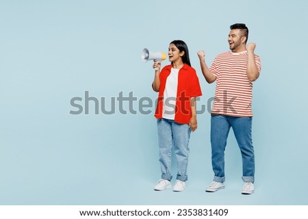 Full body young couple two friend family Indian man woman wear red casual clothes t-shirts together hold megaphone scream announces discounts sale Hurry up isolated on plain blue cyan color background