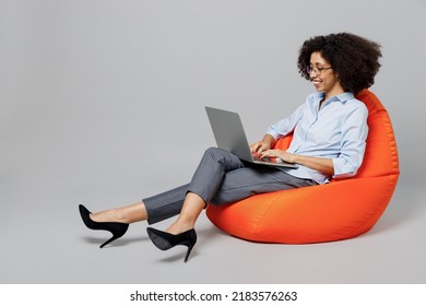 Full Body Young Employee Business Corporate Lawyer Woman Of African American Ethnicity In Formal Shirt Work In Office Sit In Bag Chair Hold Use Work On Laptop Pc Computer Isolated On Grey Background