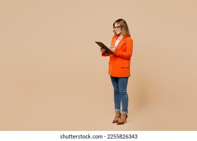 Full body young employee business woman corporate lawyer wear classic formal orange suit glasses work in office hold clipboard with paper account documents isolated on plain beige background studio - Shutterstock ID 2255826343