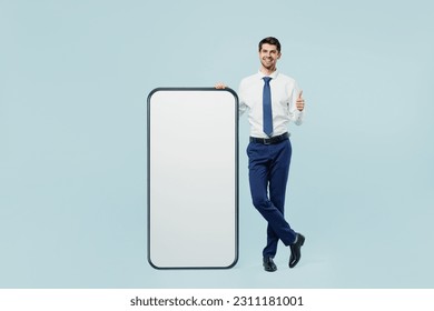 Full body young employee IT business man corporate lawyer wear classic formal shirt tie work in office big huge blank screen mobile cell phone smartphone with area isolated on plain blue background - Powered by Shutterstock