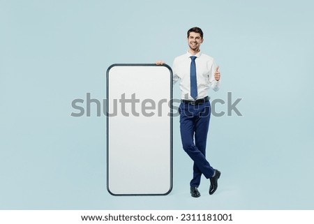 Full body young employee IT business man corporate lawyer wear classic formal shirt tie work in office big huge blank screen mobile cell phone smartphone with area isolated on plain blue background