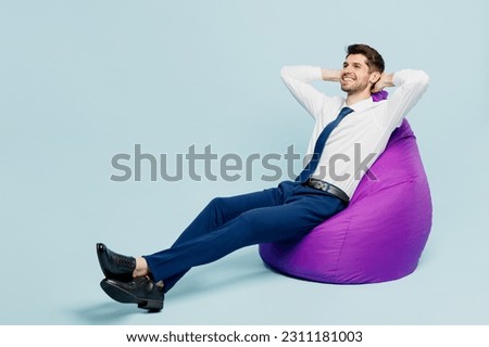 Full body young employee IT business man corporate lawyer wears classic formal shirt tie work in office sit in bag chair hold hands behind neck isolated on plain pastel light blue background studio