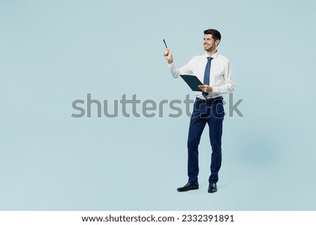 Full body young employee IT business man corporate lawyer wears classic formal shirt tie work in office hold clipboard with paper account documents point pen aside isolated on plain blue background Foto stock © 