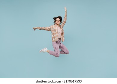 Full body young excited exultant jubilant happy woman 20s wearing casual brown shirt jump high with outstretched hands isolated on pastel plain light blue color background People lifestyle concept.