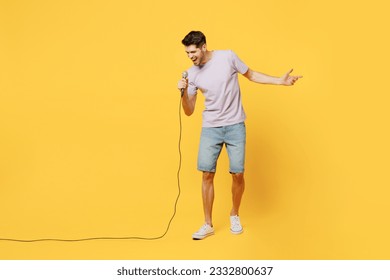 Full body young expressive singer happy man he wear light purple t-shirt casual clothes sing song in microphone at karaoke club isolated on plain yellow background studio portrait. Lifestyle concept - Powered by Shutterstock