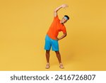 Full body young fitness trainer sporty man sportsman wear orange t-shirt do stretch lunge exercise rising hands up train in home gym isolated on plain yellow background. Workout sport fit abs concept