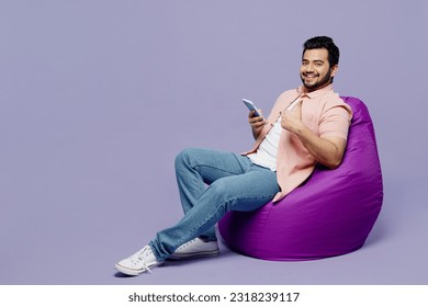 Full body young fun Indian man he wear pink shirt white t-shirt casual clothes use mobile cell phone show thumb up isolated on plain pastel light purple background studio portrait. Lifestyle concept - Powered by Shutterstock