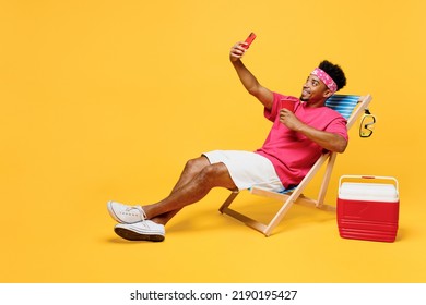 Full Body Young Fun Man He Wear Pink T-shirt Bandana Near Hotel Pool Doing Selfie Shot On Mobile Cell Phone Drink Soda Pop Water Isolated On Plain Yellow Background. Summer Vacation Sea Rest Concept